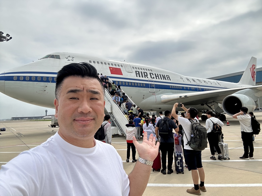 a man taking a selfie with a plane in the background