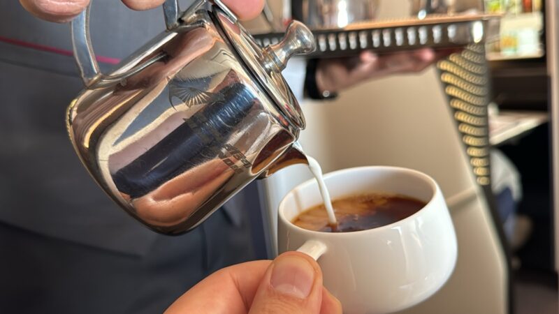 a person pouring milk into a cup of coffee