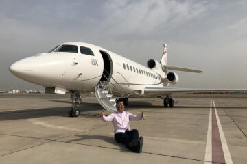 a man sitting on the ground next to an airplane