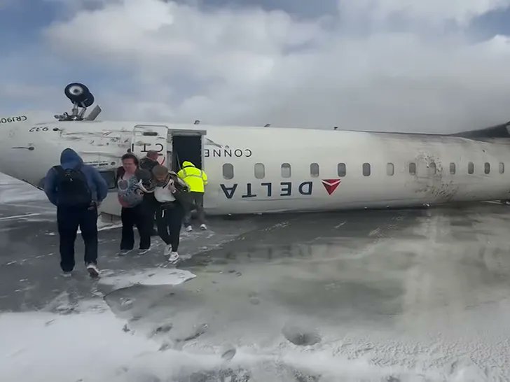 a group of people standing next to a plane that has been crashed