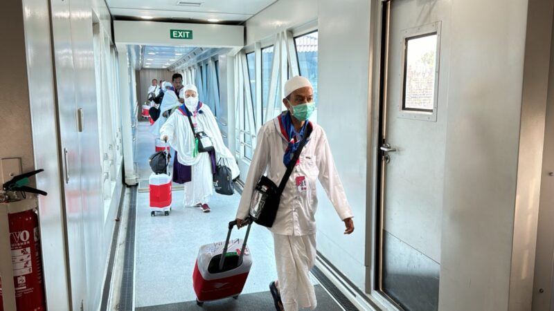 a group of people in white robes and masks walking down a hallway