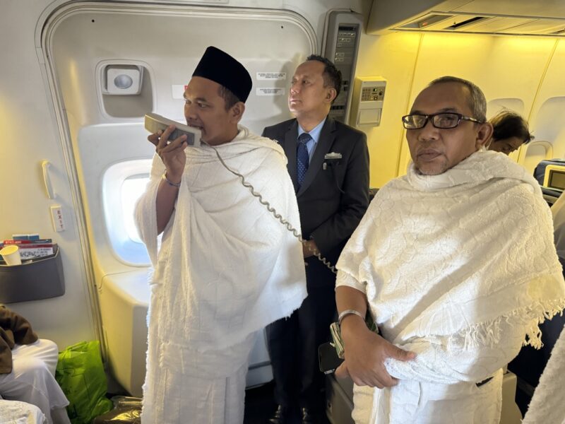 a group of men in robes standing in an airplane