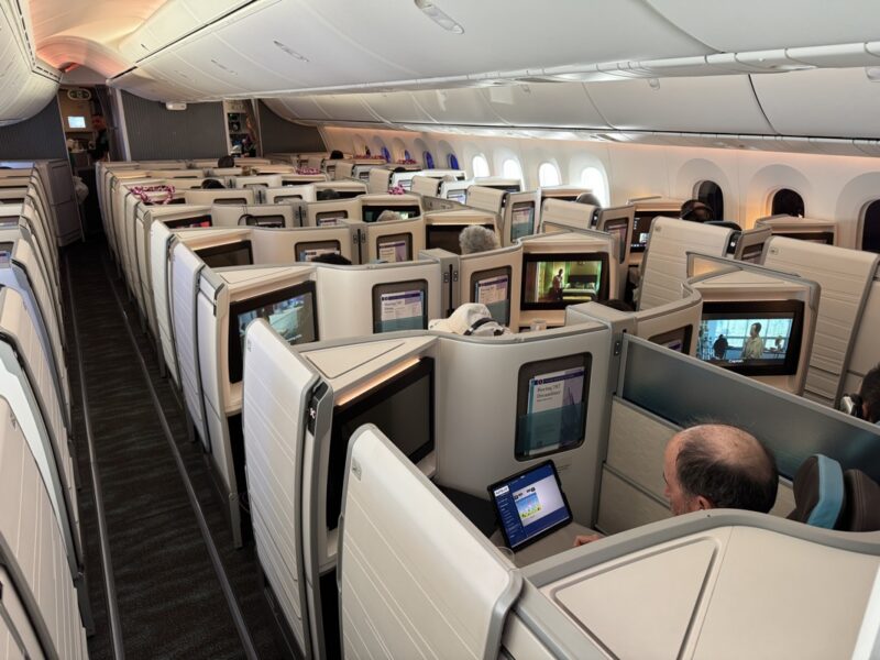 a group of people sitting in a row of seats with computers