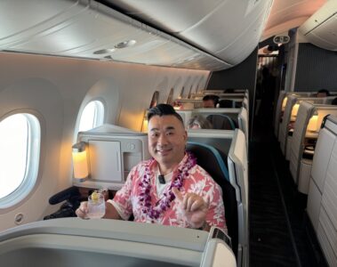 a man sitting in an airplane with a lei around his neck