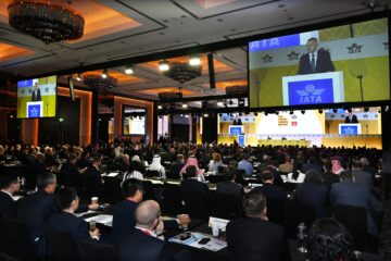 a group of people sitting in chairs in a room with a large screen