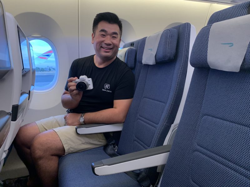 a man sitting in an airplane with a camera