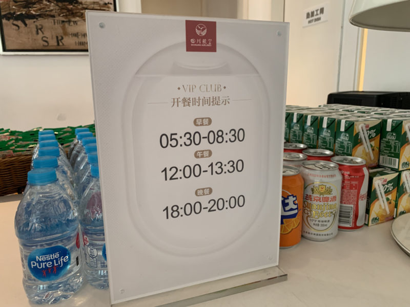 a sign on a table with drinks and cans of soda